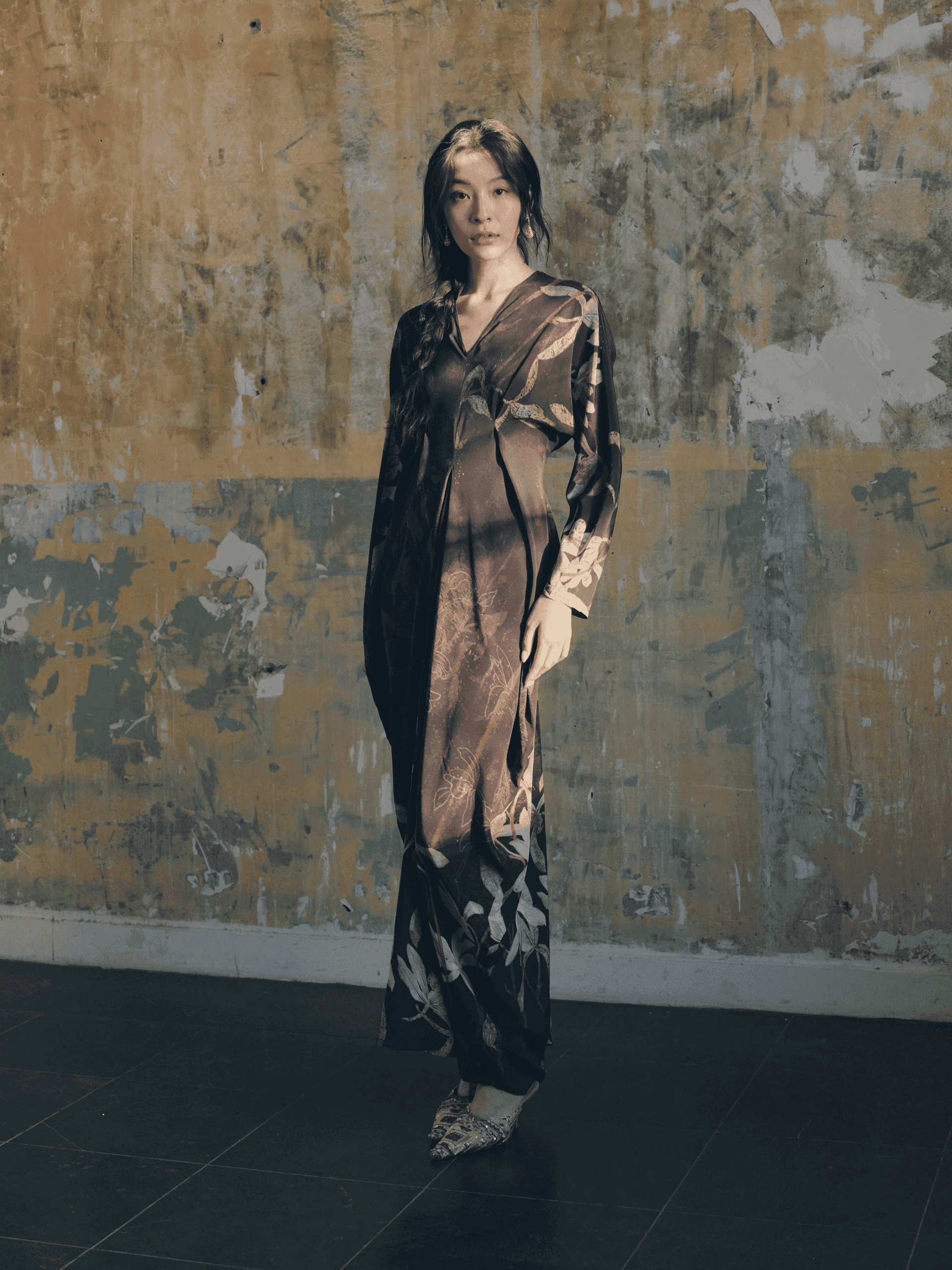 Nine Orchids collection look — editorial full-bleed photograph of a model in flowing natural-fabric garments among orchid blooms
